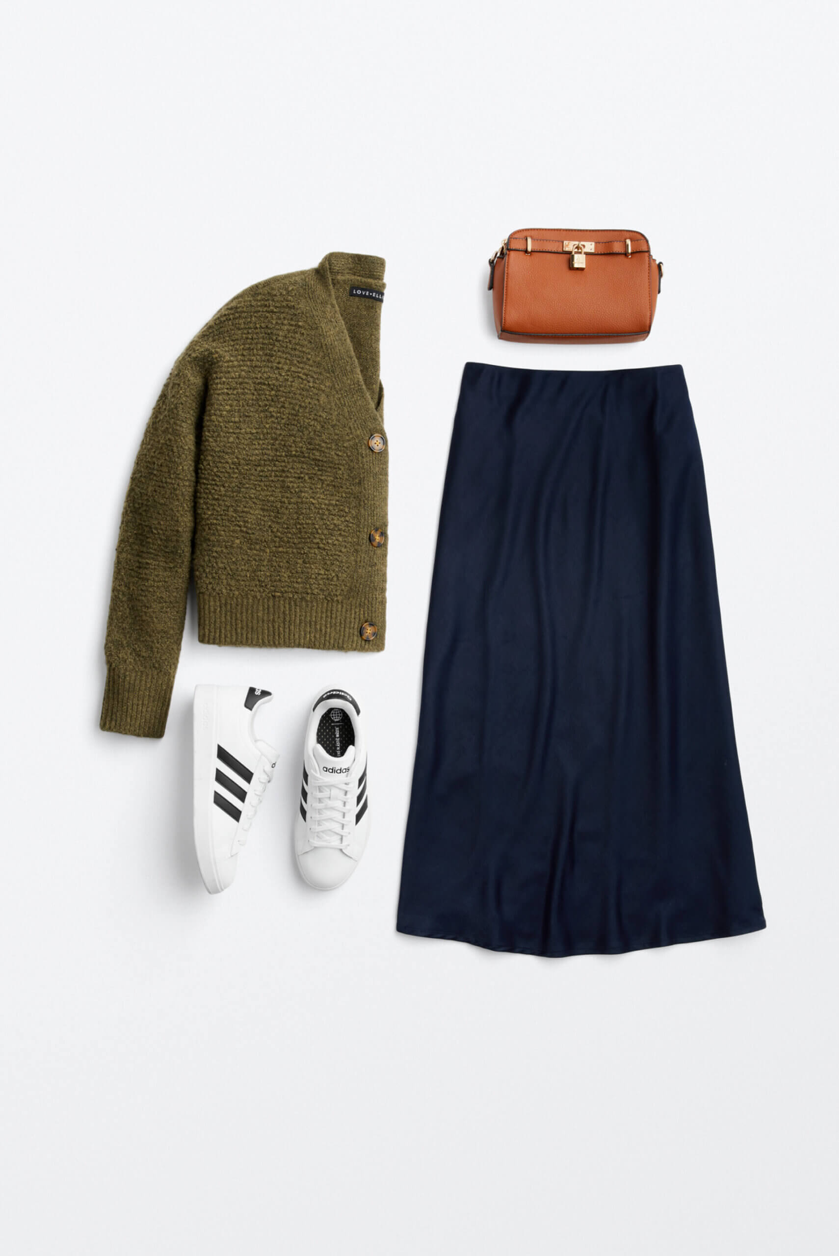 Alt text: A green cardigan, blue maxi skirt, brown clutch purse and white Adidas sneakers arranged together for outfit inspiration. 